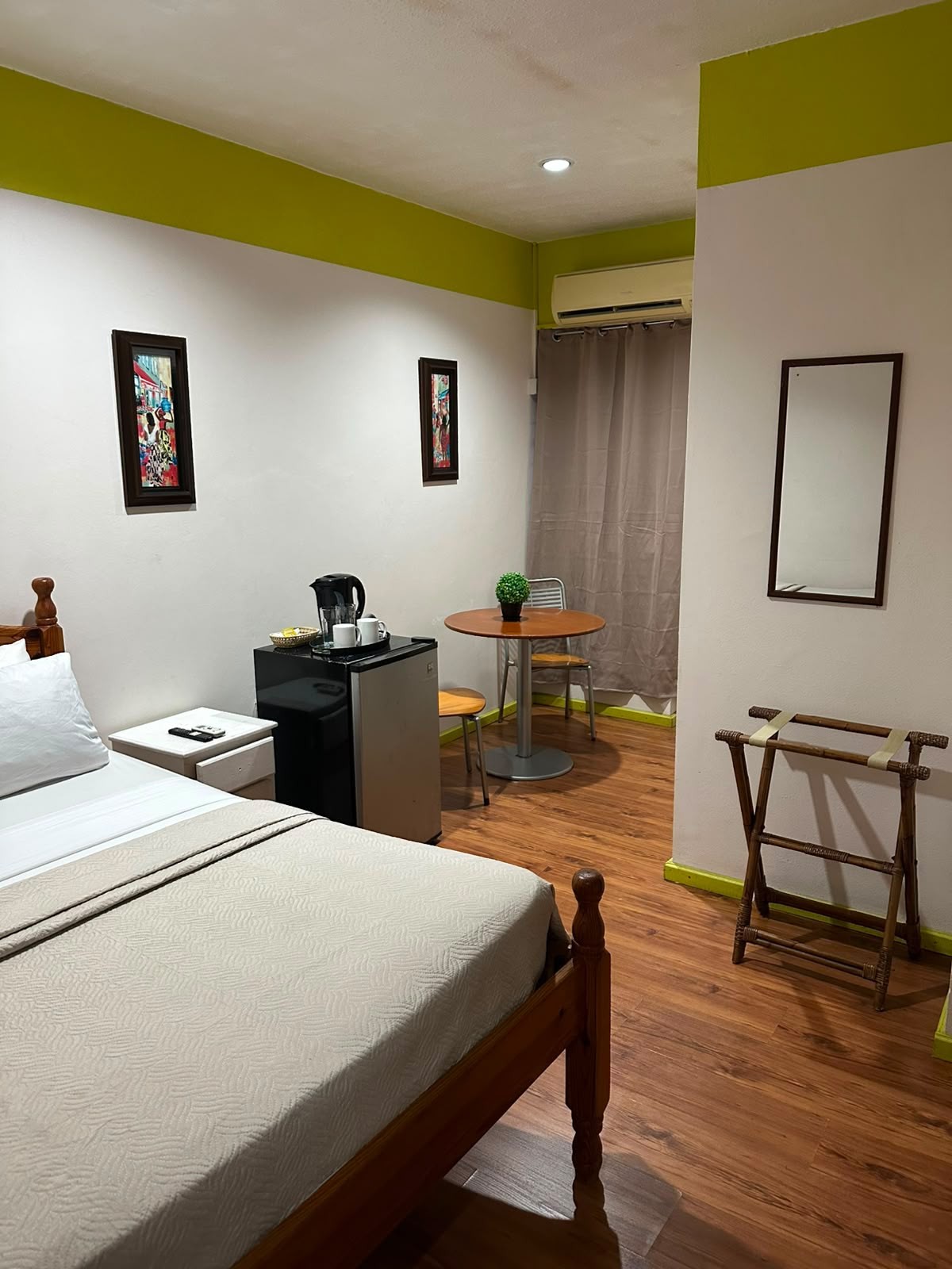 Guest room with green wall accent and wooden floors
