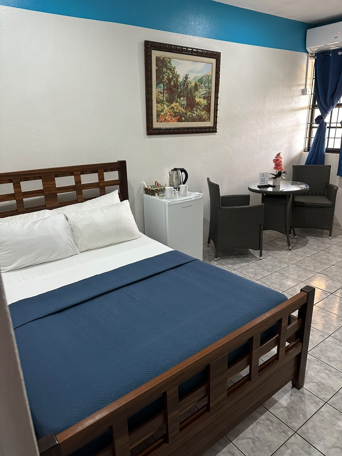 Room with wooden bed frame, teal bedding and a seating area